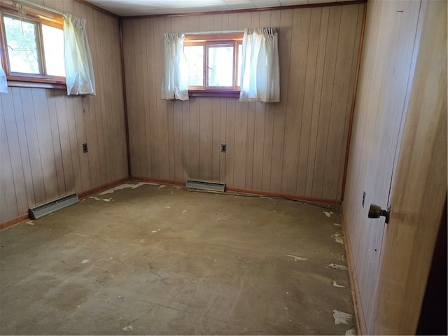 spare room with baseboard heating and wooden walls