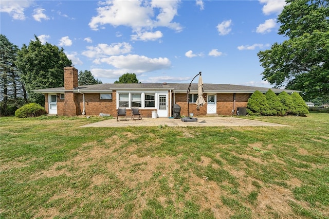 rear view of house featuring a lawn and a patio