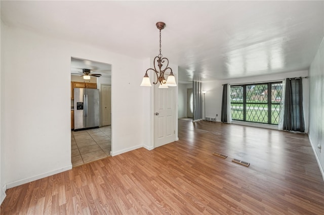 unfurnished dining area with ceiling fan with notable chandelier and light hardwood / wood-style floors