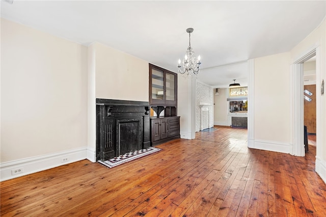 unfurnished living room with hardwood / wood-style floors and an inviting chandelier