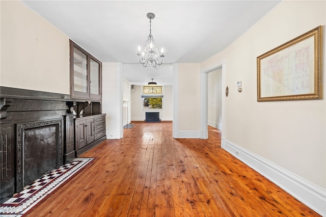 unfurnished living room featuring an inviting chandelier and wood-type flooring