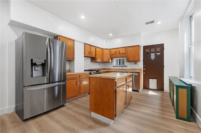 kitchen with a kitchen island, sink, appliances with stainless steel finishes, and light hardwood / wood-style floors