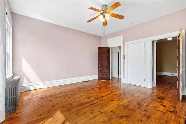 unfurnished bedroom with ceiling fan, hardwood / wood-style floors, and radiator heating unit