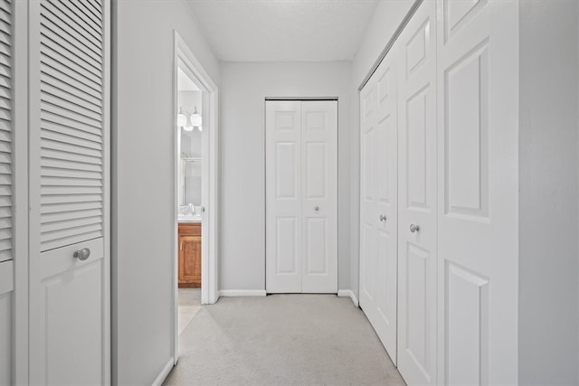 hallway with light carpet and a textured ceiling