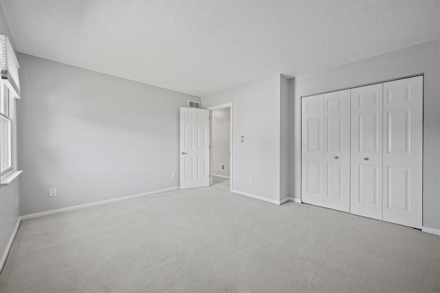 unfurnished bedroom with light colored carpet, a textured ceiling, and a closet