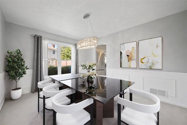 carpeted dining space featuring a textured ceiling and a chandelier