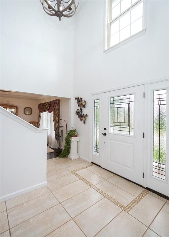 tiled entryway featuring a towering ceiling and an inviting chandelier