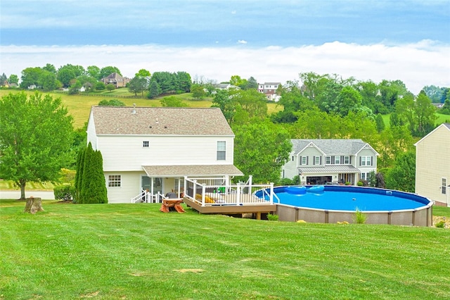 rear view of house with a swimming pool side deck and a yard