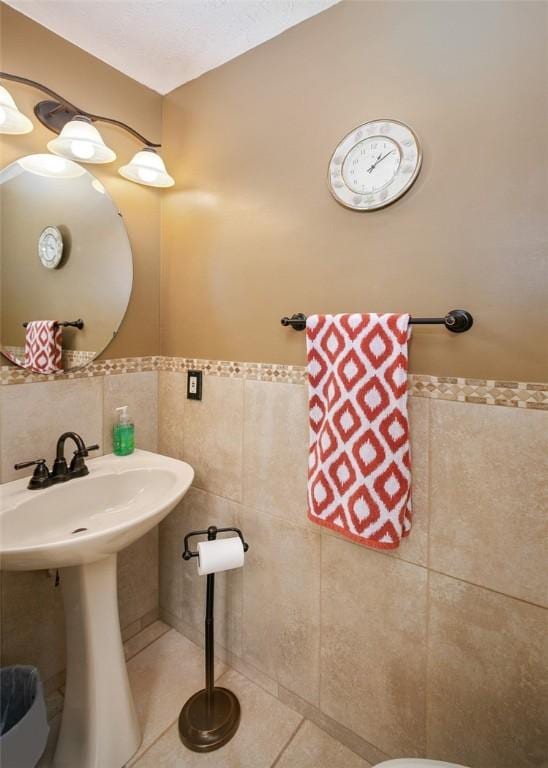 bathroom with tile patterned floors, sink, and tile walls