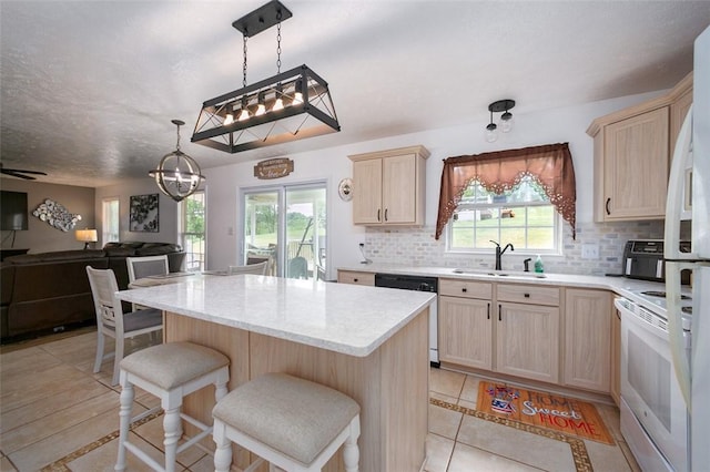 kitchen featuring a breakfast bar, white appliances, a wealth of natural light, and sink