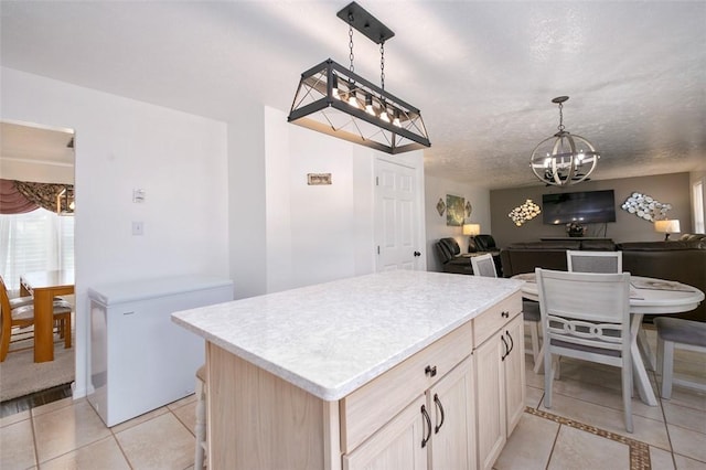 kitchen featuring light brown cabinets, refrigerator, light tile patterned floors, decorative light fixtures, and a chandelier