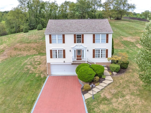 colonial home featuring a front yard and a garage