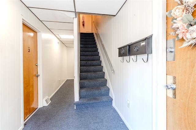 staircase with wooden walls and carpet floors