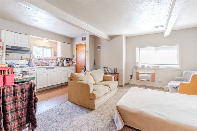 bedroom featuring sink, beam ceiling, a textured ceiling, and light hardwood / wood-style flooring