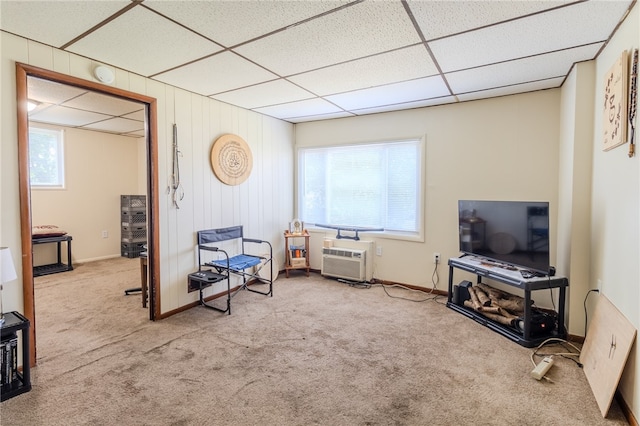 living area featuring light colored carpet, a wall mounted air conditioner, wooden walls, and a drop ceiling