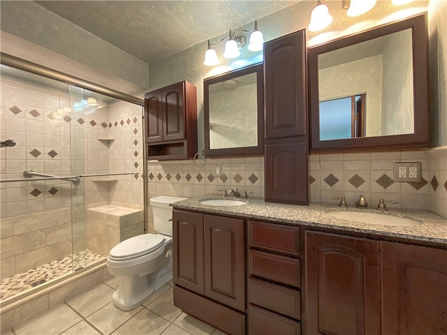 bathroom with a shower with shower door, vanity, tasteful backsplash, toilet, and tile patterned floors