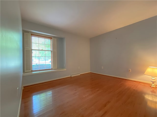 unfurnished room with a baseboard radiator and wood-type flooring