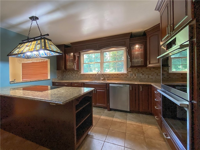 kitchen with stainless steel appliances, a center island, sink, hanging light fixtures, and light tile patterned flooring