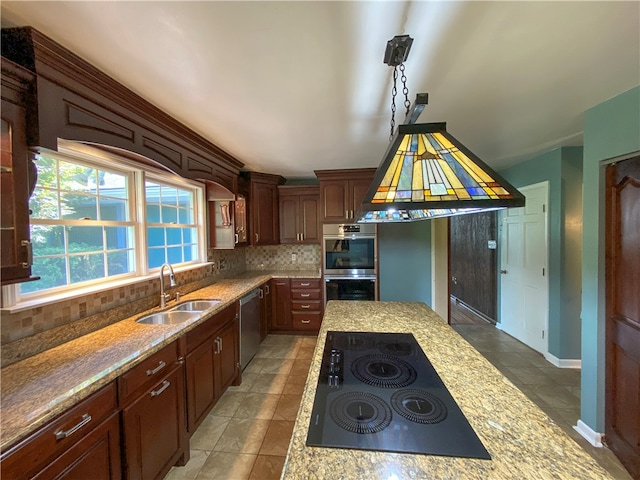 kitchen featuring light stone counters, stainless steel appliances, sink, and decorative backsplash