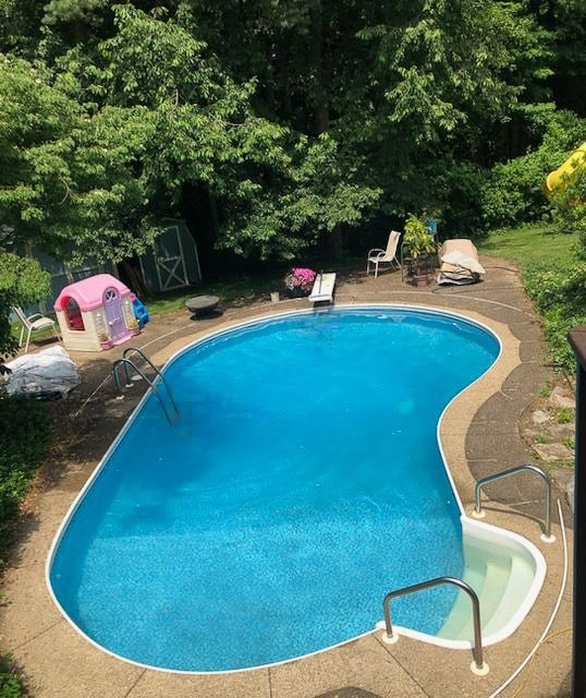 view of pool with a storage shed and a patio area