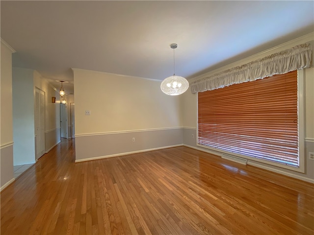 unfurnished room with ornamental molding, a chandelier, and hardwood / wood-style floors