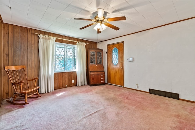 spare room featuring ornamental molding, ceiling fan, wood walls, and carpet floors