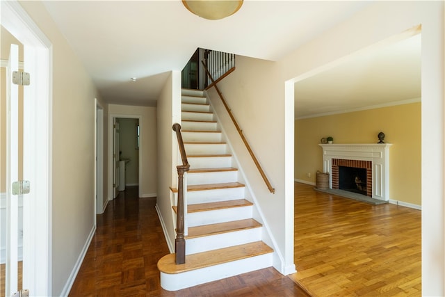 stairs with crown molding, hardwood / wood-style flooring, and a fireplace