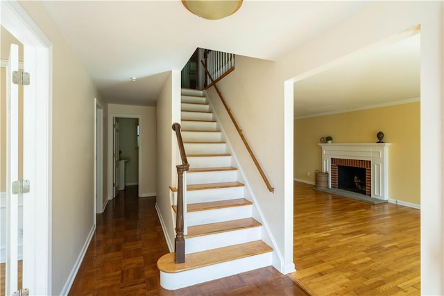 stairway featuring parquet floors, a fireplace, and ornamental molding