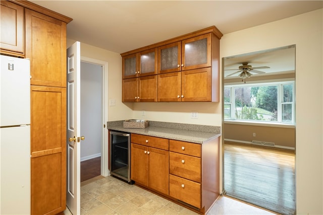 kitchen with white refrigerator, light stone countertops, beverage cooler, and ceiling fan