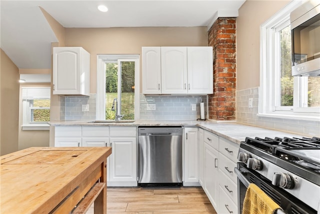 kitchen with a wealth of natural light, stainless steel appliances, and white cabinetry