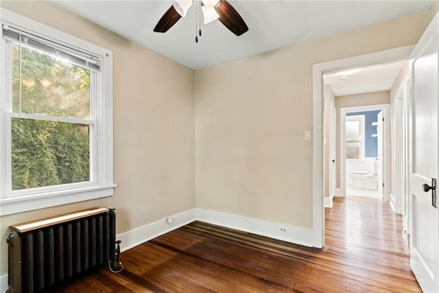 spare room featuring ceiling fan, radiator heating unit, and hardwood / wood-style flooring