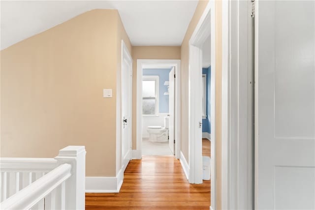 hallway featuring light wood-type flooring and vaulted ceiling