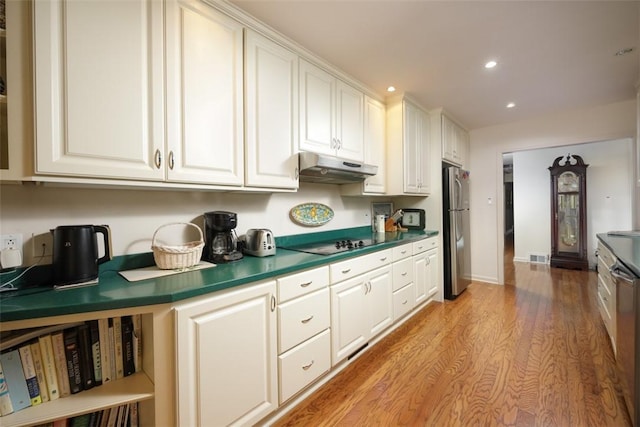 kitchen with white cabinetry, under cabinet range hood, black electric cooktop, and freestanding refrigerator