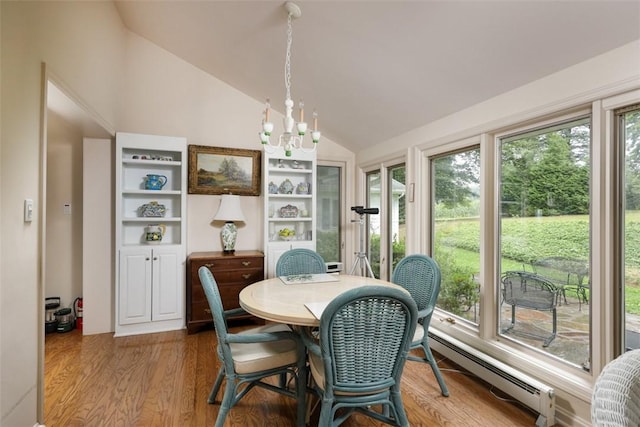 dining room with vaulted ceiling, a healthy amount of sunlight, a baseboard heating unit, and wood finished floors