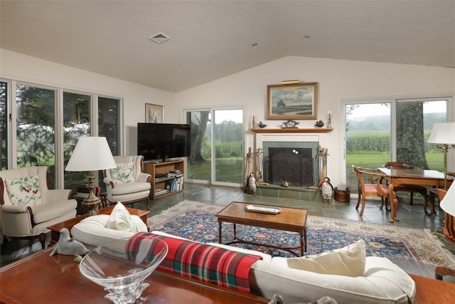 living area with a tiled fireplace, vaulted ceiling, visible vents, and stone tile flooring