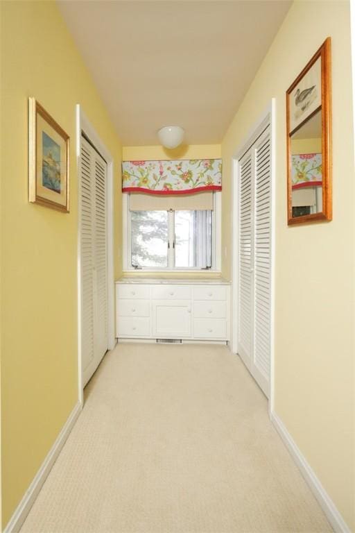 hall featuring light carpet and baseboards