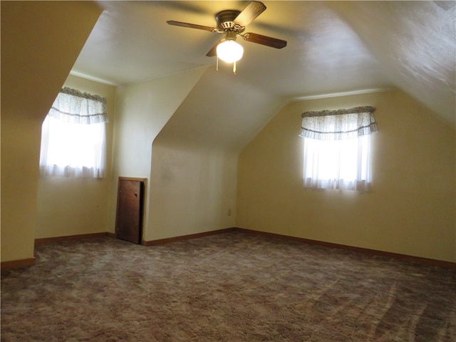 bonus room featuring a wealth of natural light, vaulted ceiling, dark carpet, and ceiling fan