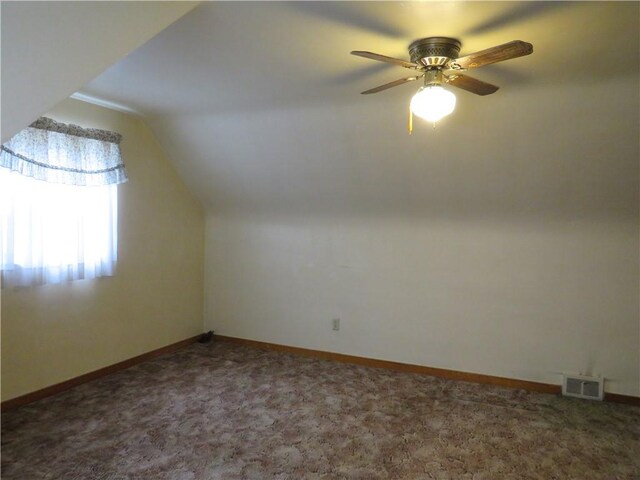 additional living space with dark colored carpet, lofted ceiling, and ceiling fan