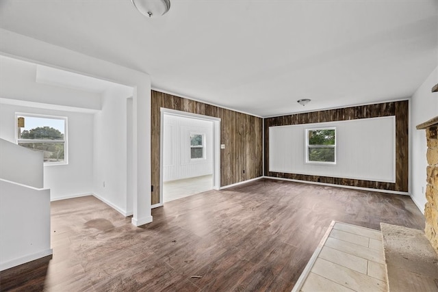 spare room with plenty of natural light, wood-type flooring, and wooden walls