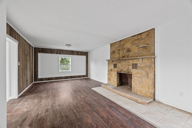 unfurnished living room featuring a fireplace, light wood-type flooring, and wood walls