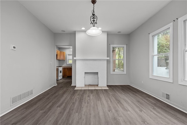 unfurnished living room featuring wood-type flooring and a brick fireplace