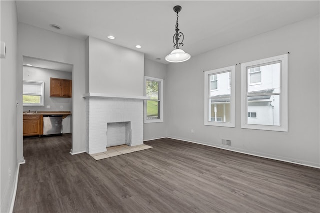 unfurnished living room featuring sink, a fireplace, dark hardwood / wood-style flooring, and a wealth of natural light