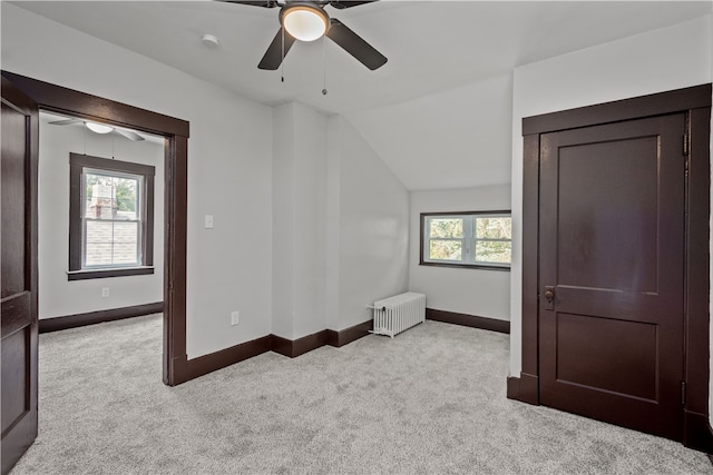 bonus room with lofted ceiling, ceiling fan, light colored carpet, and radiator