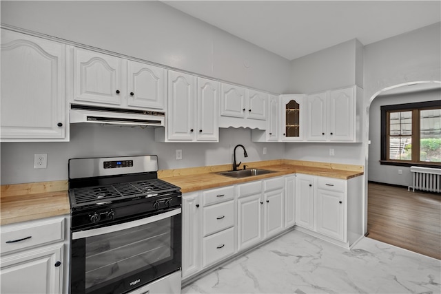 kitchen with stainless steel range with gas cooktop, ventilation hood, white cabinets, and sink