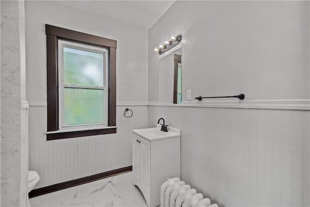 bathroom with wooden walls, vanity, radiator, and toilet