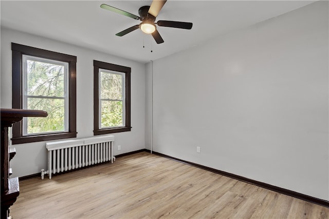 unfurnished room with ceiling fan, radiator heating unit, and light hardwood / wood-style flooring