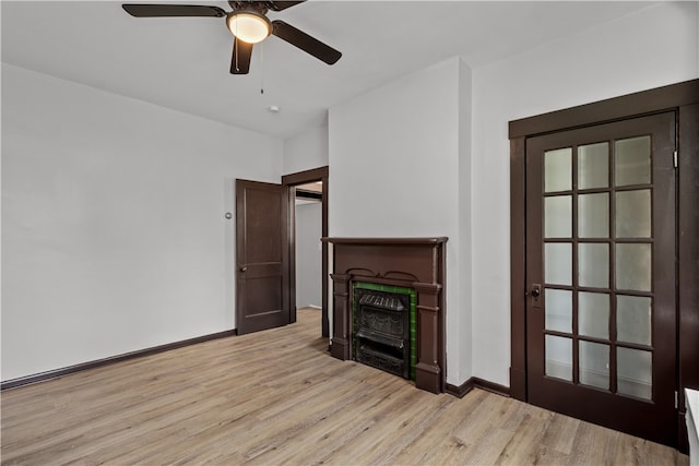 unfurnished living room with ceiling fan, a fireplace, and light hardwood / wood-style floors