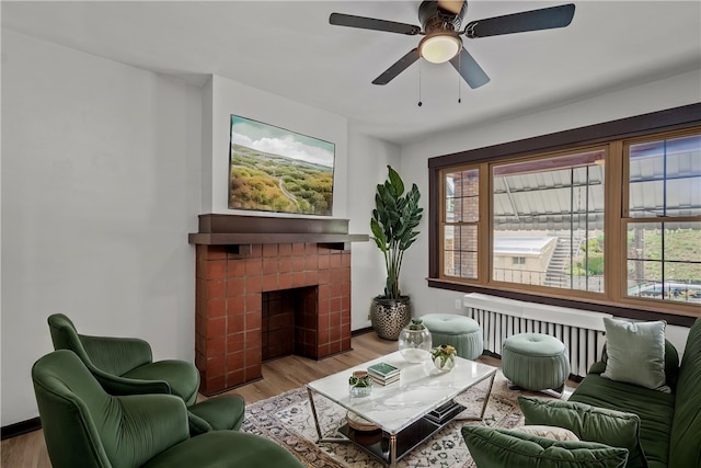 living room with ceiling fan, a tile fireplace, and light hardwood / wood-style floors