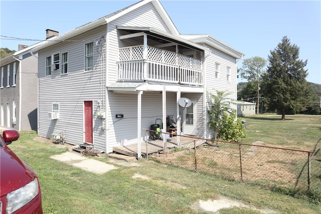 back of house with a balcony and a yard