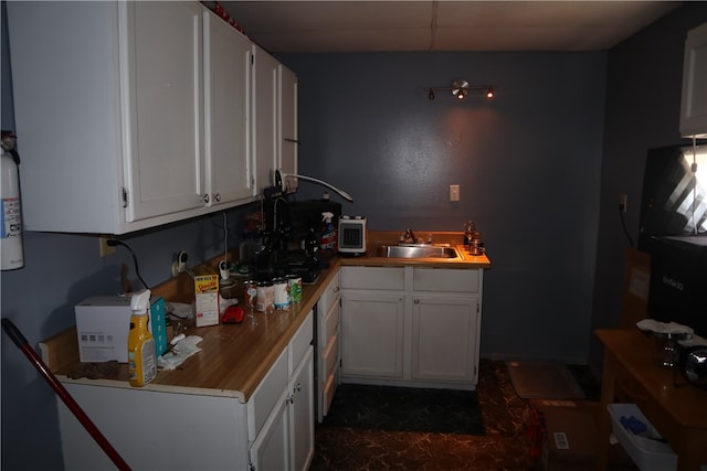 kitchen featuring butcher block countertops, sink, and white cabinets